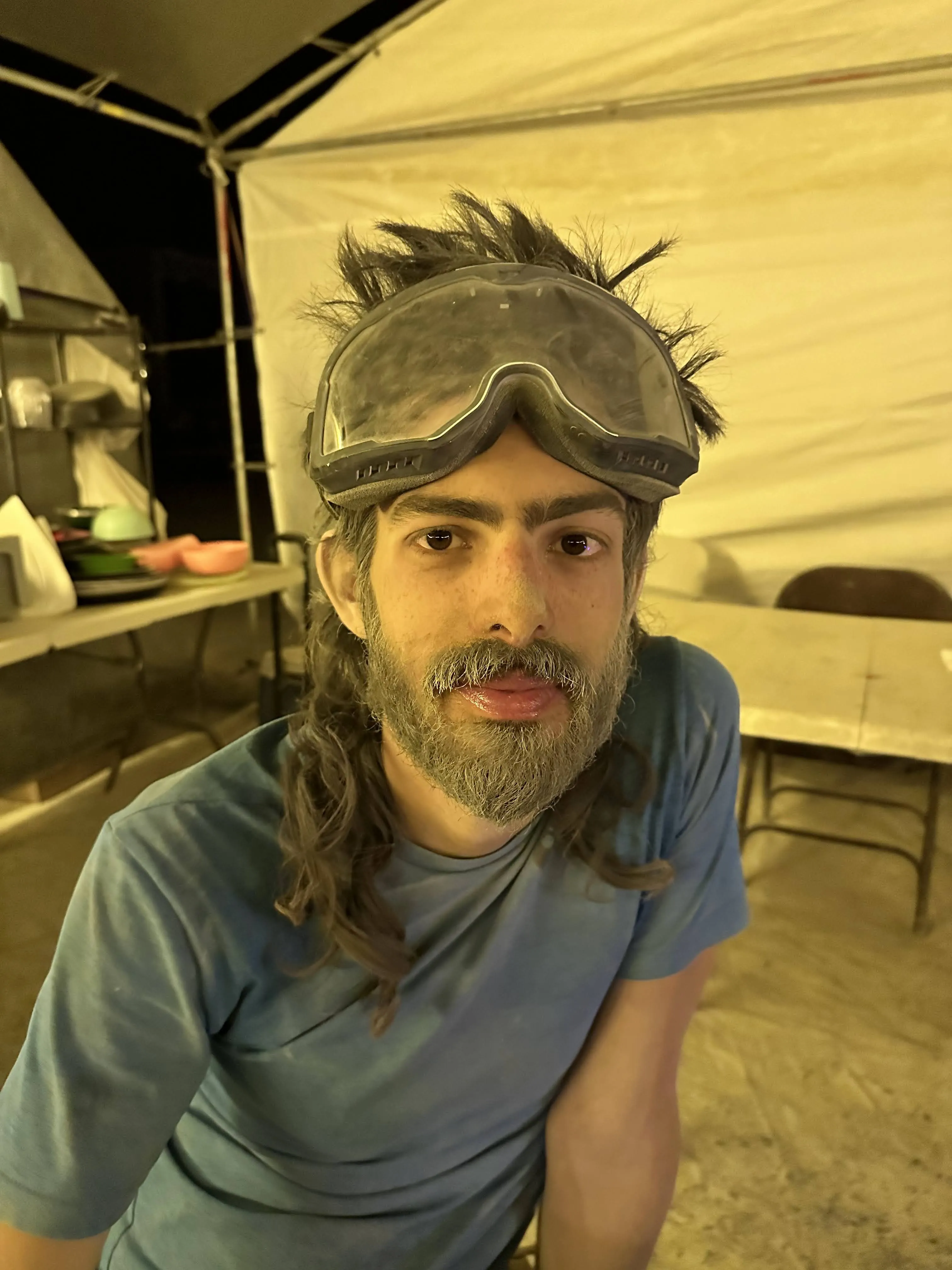 Yoav at Burning Man after a sandstorm, hair and beard covered in sand, dusty goggles on his head