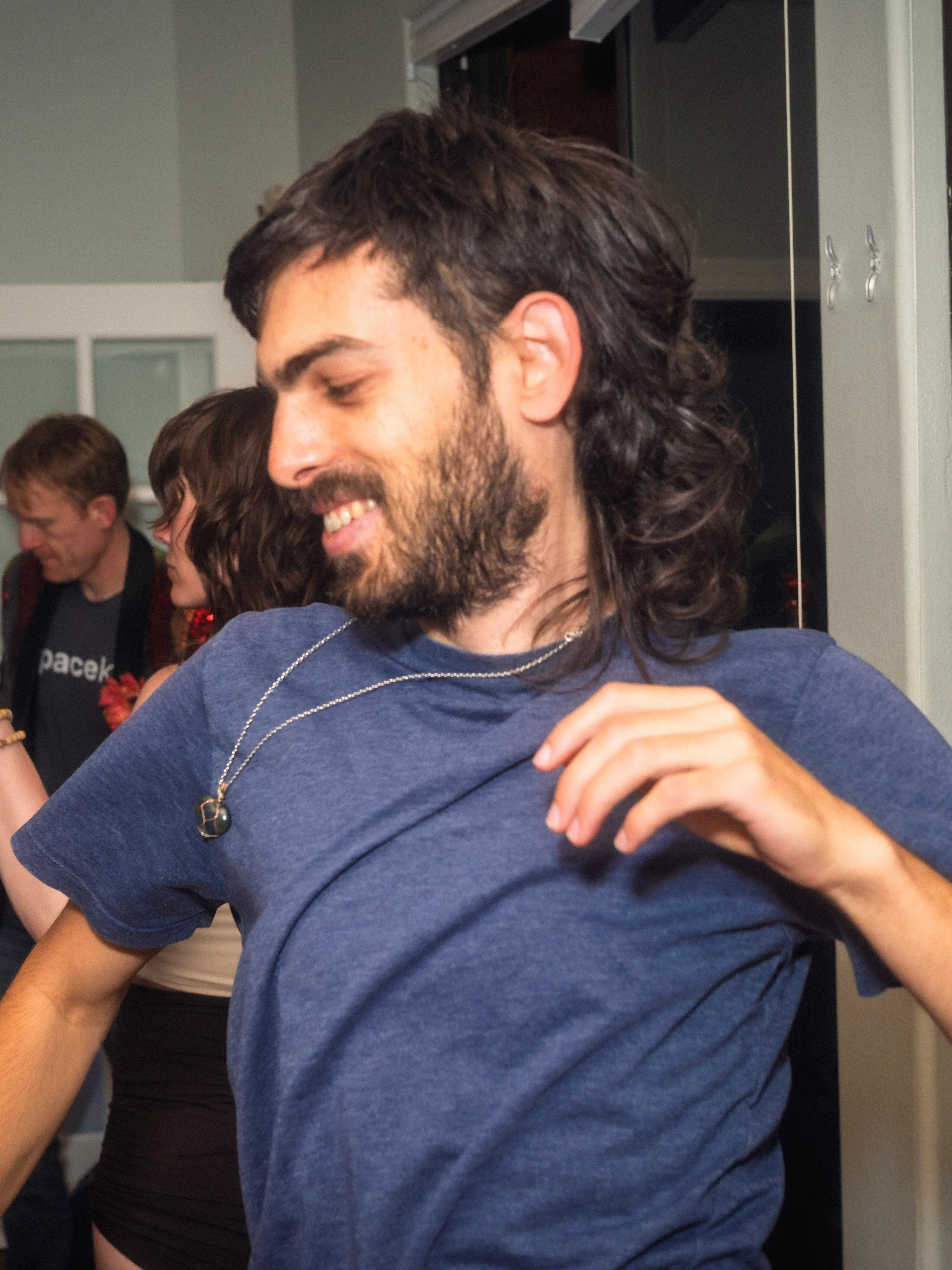 Yoav dancing at a house party, smiling and looking to the side